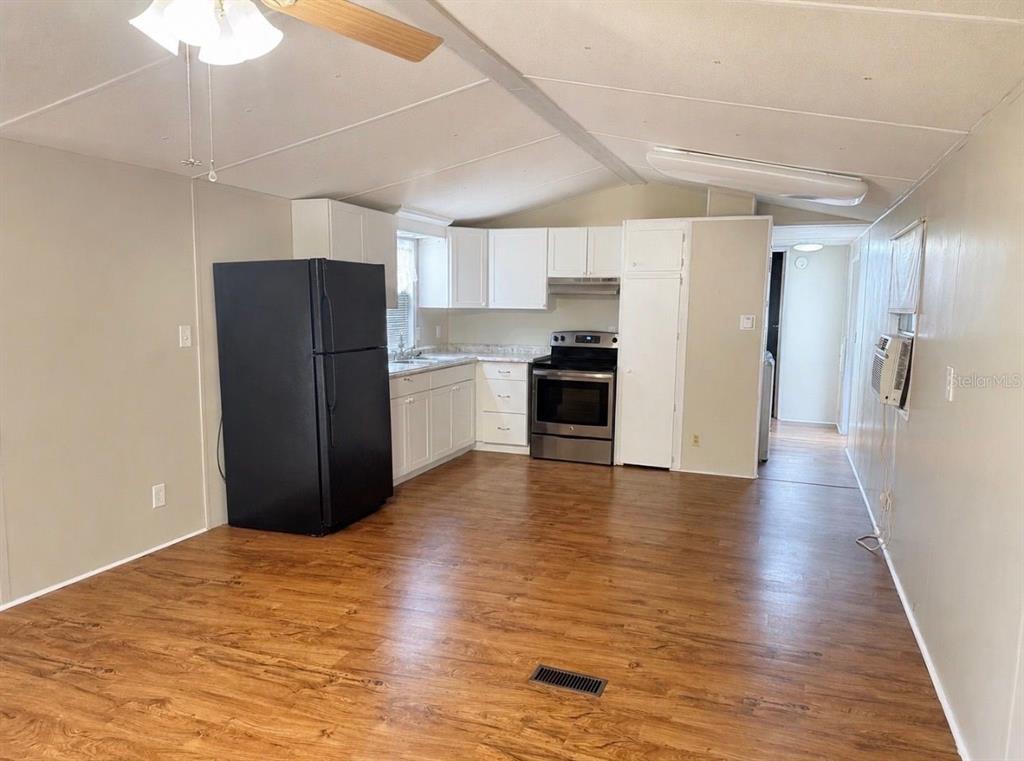 A kitchen with white cabinets, stainless steel appliances, and wood-look flooring in an open space — 7920 SUNRUNNER ROAD, NEW PORT RICHEY, FL