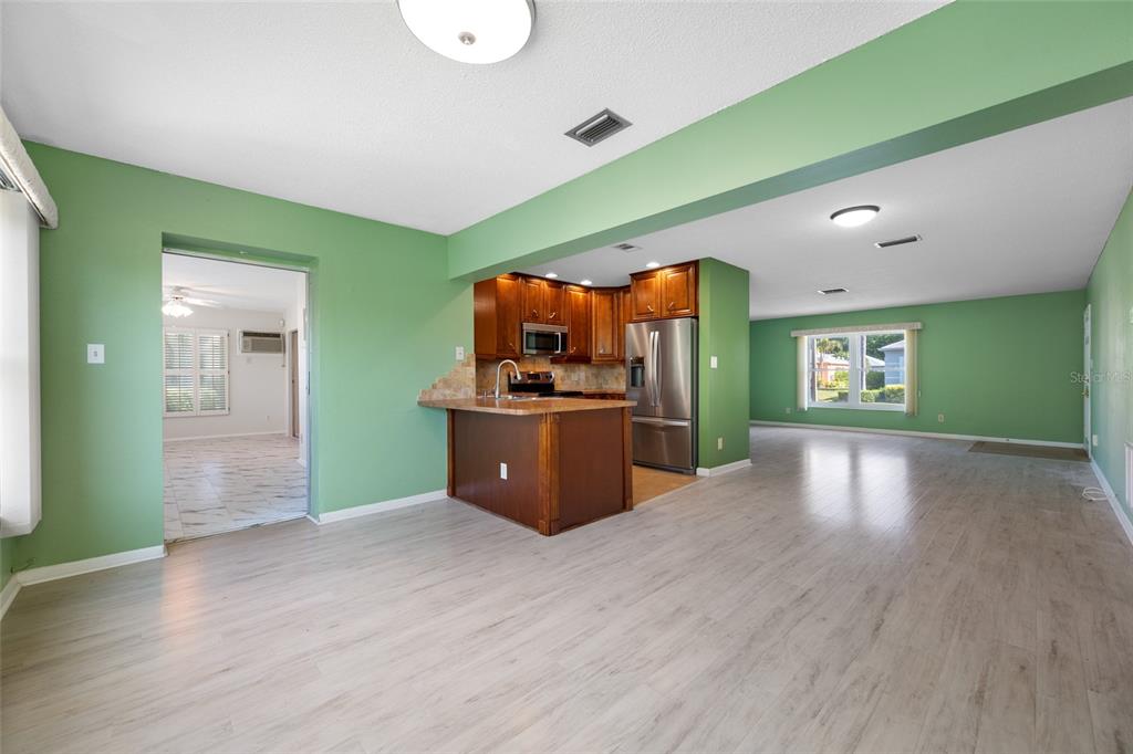 An open-concept living area features light wood flooring, green walls, and a kitchen with wood cabinets — 8440 BRENTWOOD ROAD UNIT 8440, SEMINOLE, FL