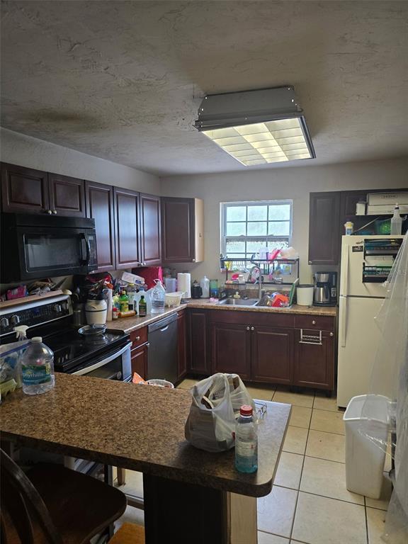 A kitchen with dark wood cabinets, laminate countertops, a white refrigerator, and a fluorescent light — 11069 NE 14TH AVENUE, BRANFORD, FL