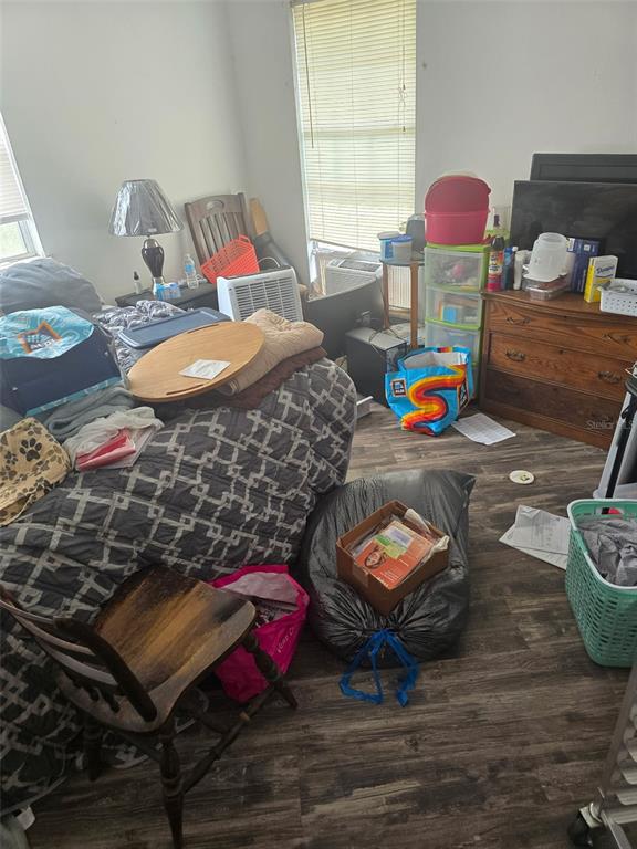 A bedroom with wood-look flooring, a bed with a patterned comforter, and various storage items — 11069 NE 14TH AVENUE, BRANFORD, FL