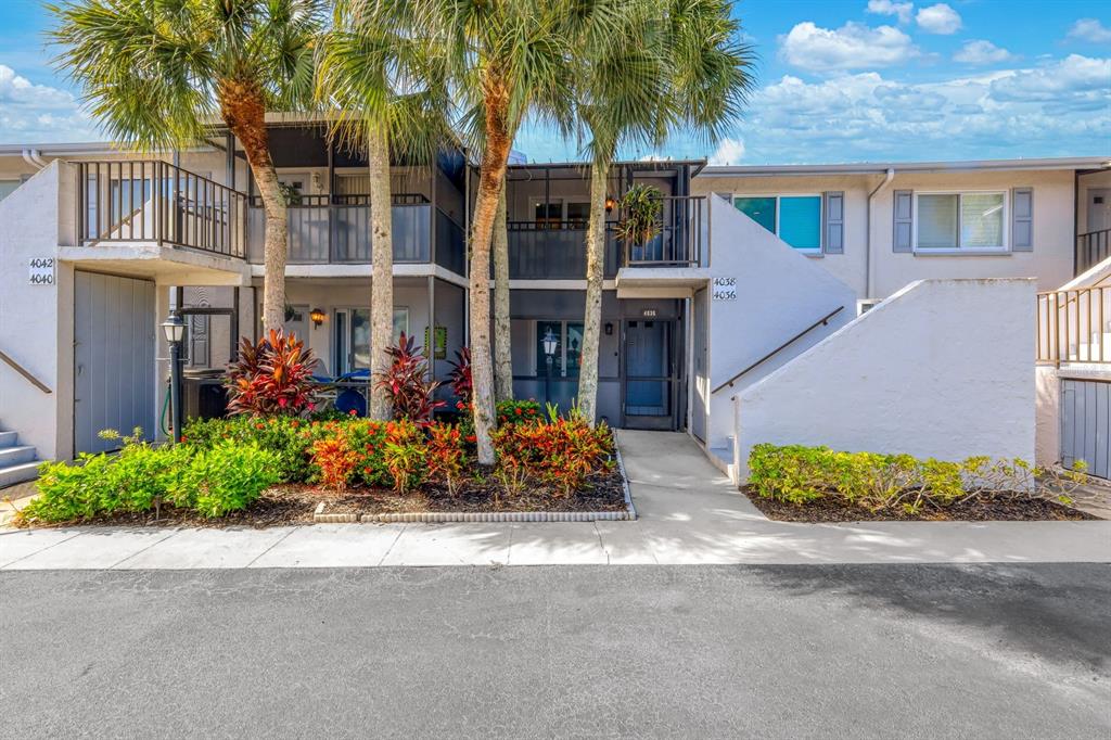An aerial view shows a multi-unit residential building with a parking lot and a pond — 4038 NORTHLIGHT DRIVE UNIT 1506, NAPLES, FL