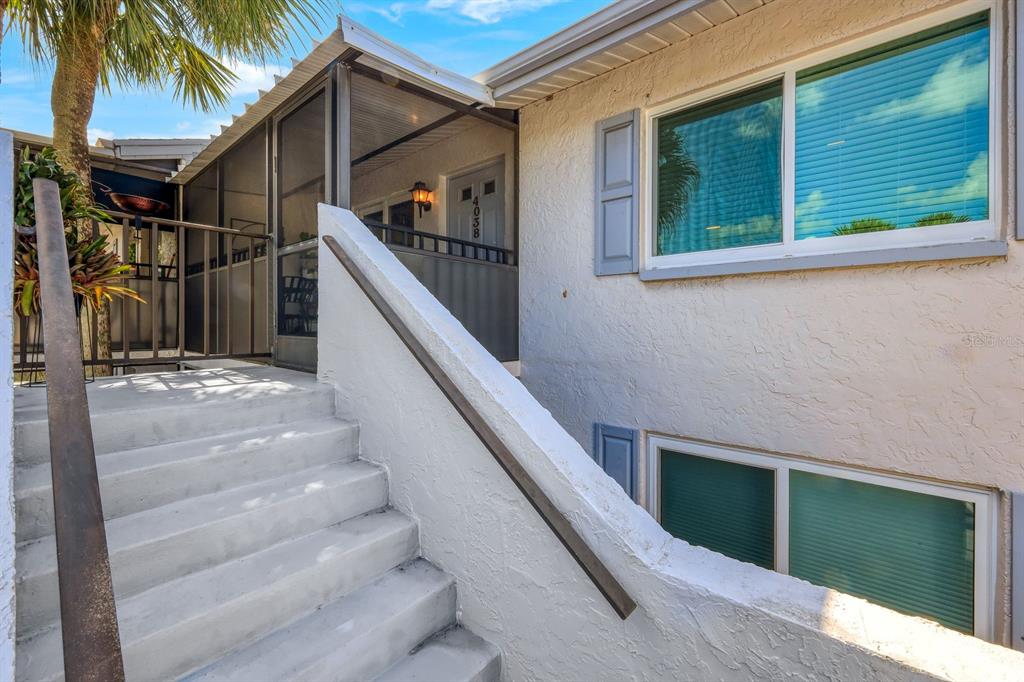 Concrete stairs lead up to a screened-in porch entrance of a white stucco building — 4038 NORTHLIGHT DRIVE UNIT 1506, NAPLES, FL
