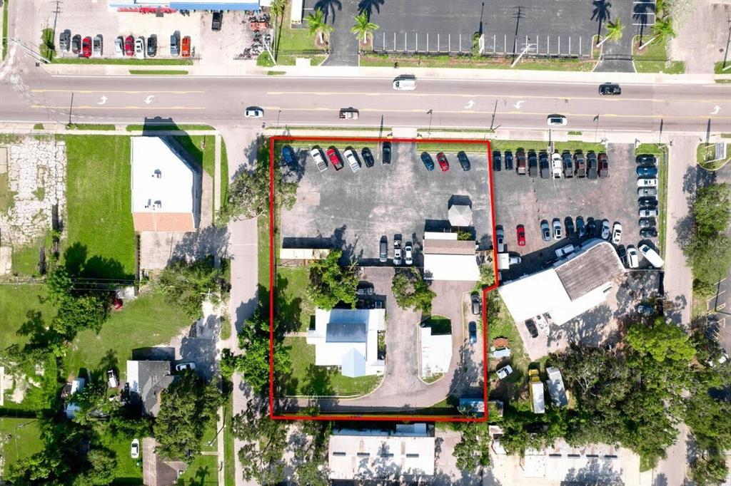 This aerial view shows a commercial property with a parking lot and two small buildings — 1827 9TH STREET W, BRADENTON, FL