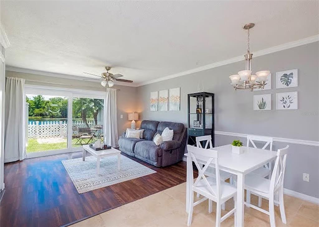 A living and dining area features wood-look flooring, a gray sofa, and a sliding glass door — 13812 ORANGE SUNSET DRIVE UNIT 0, TAMPA, FL