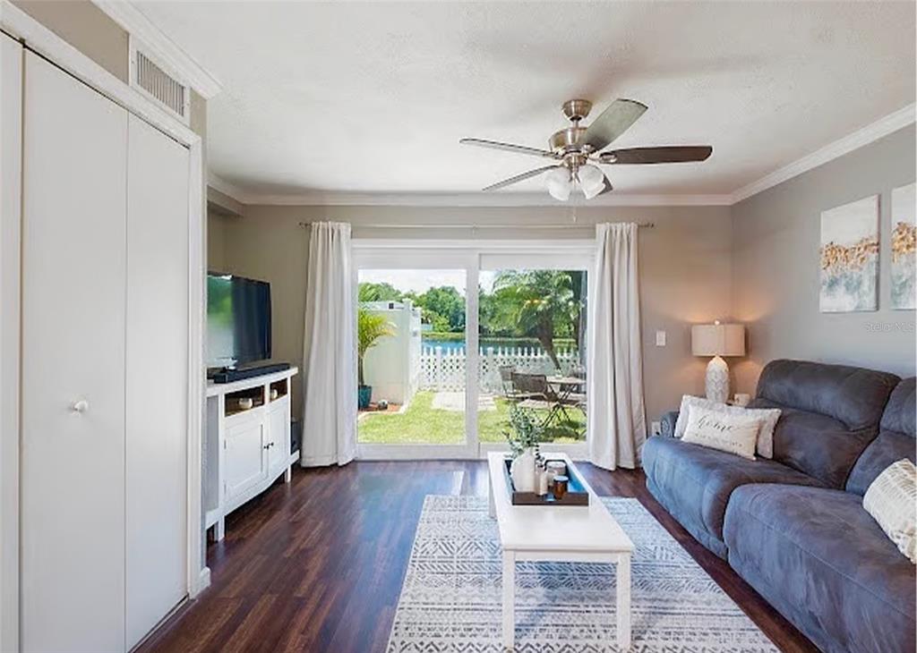 A living room features dark wood floors, a gray sofa, and sliding doors to a patio — 13812 ORANGE SUNSET DRIVE UNIT 0, TAMPA, FL