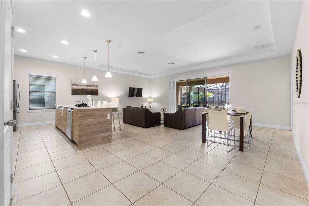 A modern kitchen features a large white island with bar seating and wood-grain cabinetry — 194 AIDANS LANDING, HAINES CITY, FL