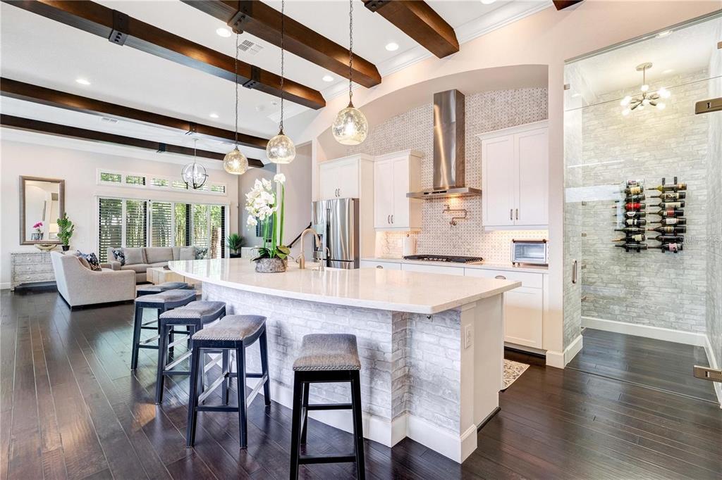 A kitchen with a white island, wooden ceiling beams, and a glass-enclosed wine display — 8449 VIA VITTORIA WAY, ORLANDO, FL