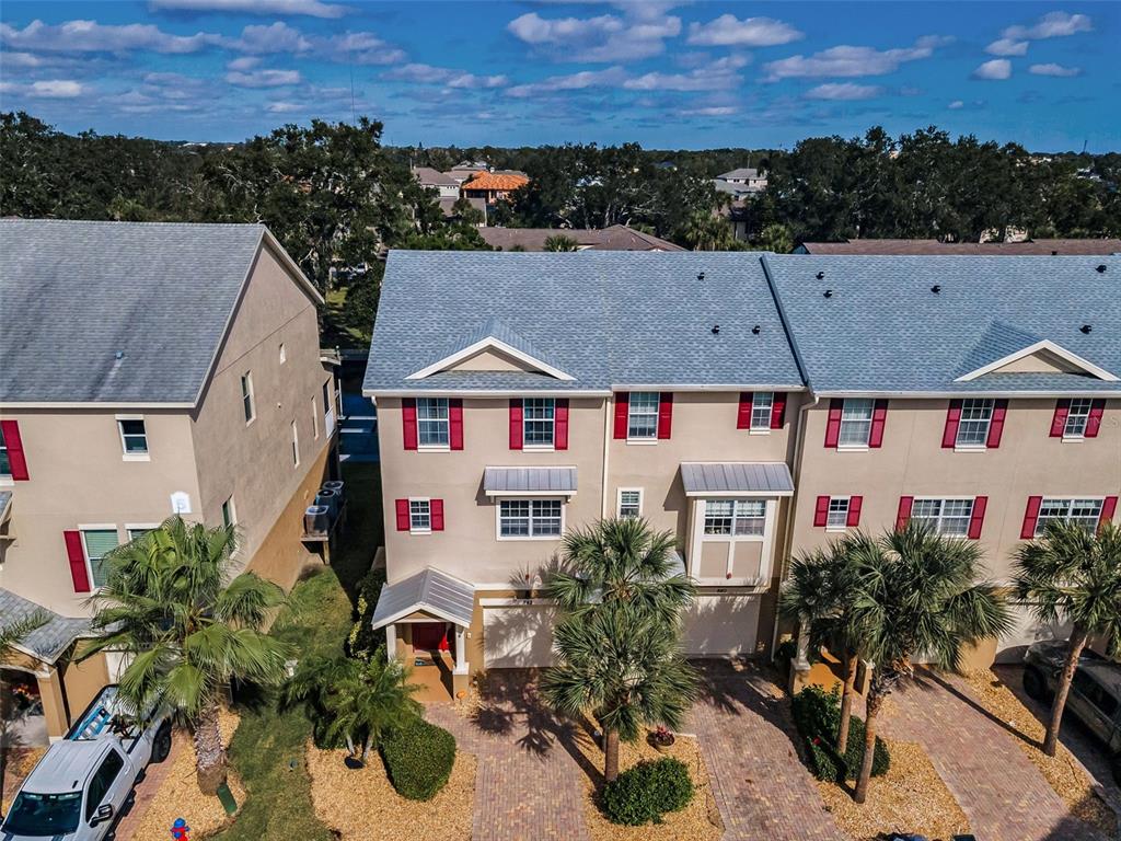 An aerial view shows a row of three-story townhouses with beige stucco and red shutters — 842 CALLISTA CAY LOOP, TARPON SPRINGS, FL