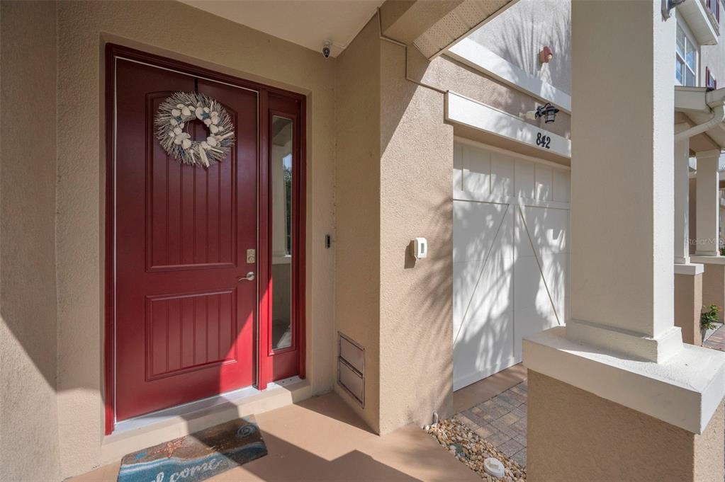 A red front door with a wreath and a white garage door on a house — 842 CALLISTA CAY LOOP, TARPON SPRINGS, FL