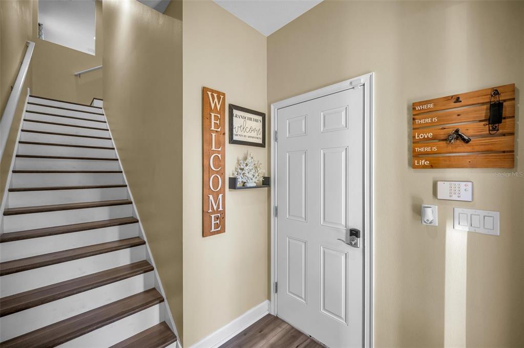An entryway features a staircase, a white front door, and wall-mounted decorative signs — 842 CALLISTA CAY LOOP, TARPON SPRINGS, FL