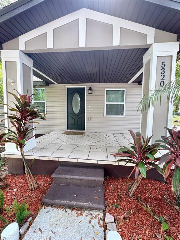 A front porch with tiled flooring leads to a dark green door under a gable — 5320 CHERRY AVENUE, SEFFNER, FL