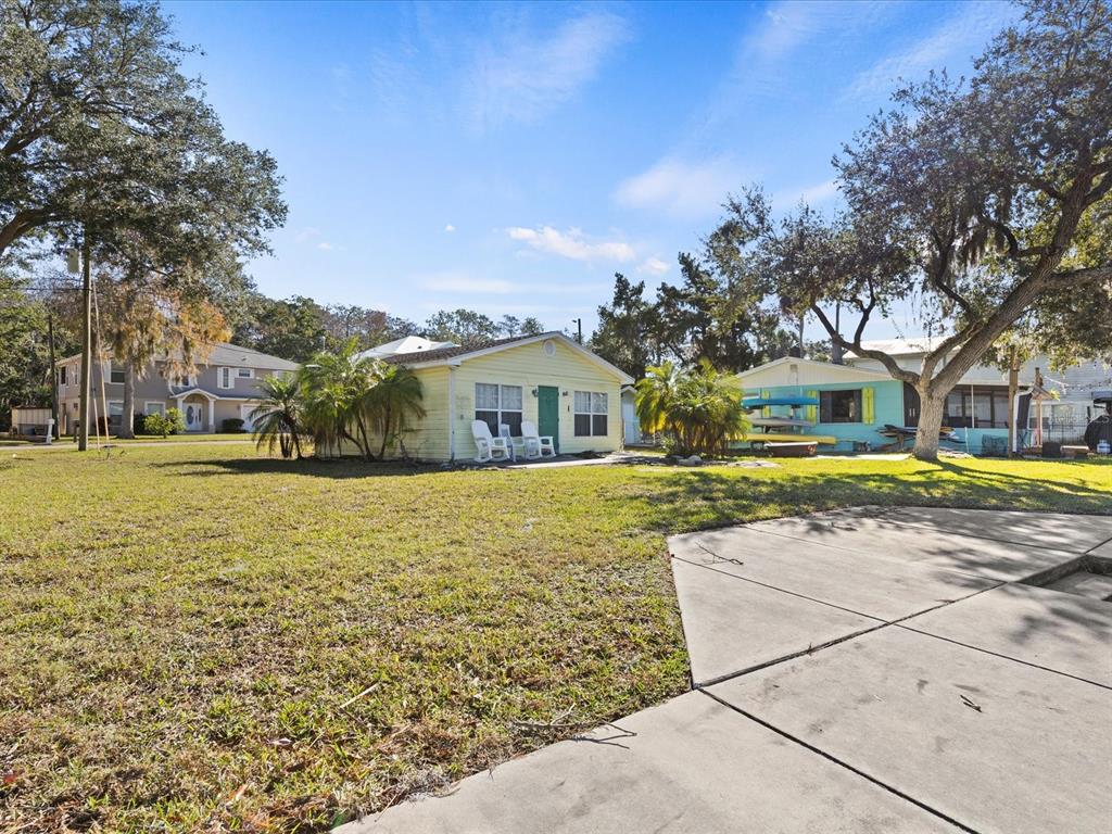A yellow house and a light blue house sit on a grassy lot with trees — 7255 TROPICAL DRIVE, WEEKI WACHEE, FL