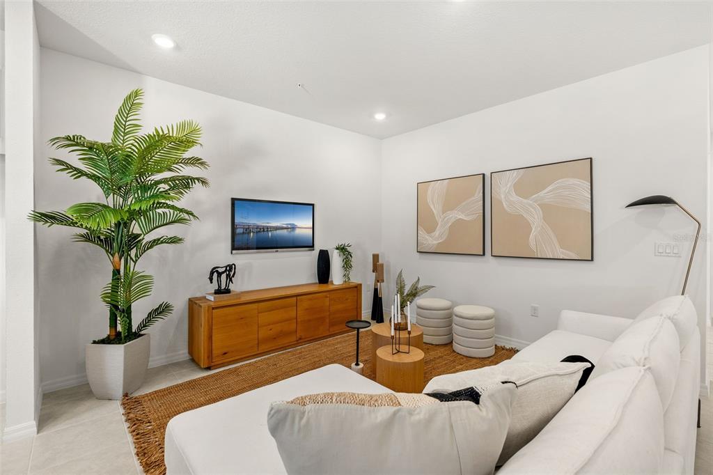 A living room features a white sofa, a wooden media console, and a large potted plant — 672 EMERALD GROVE DRIVE, APOPKA, FL