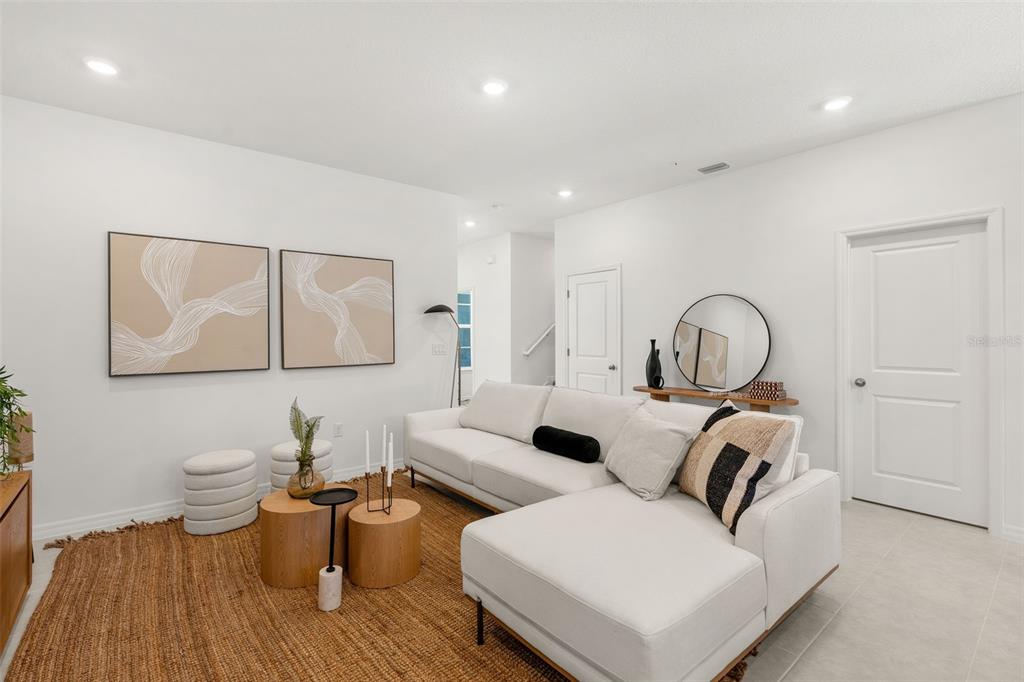 A modern living room features a white sectional sofa, a jute rug, and abstract wall art — 672 EMERALD GROVE DRIVE, APOPKA, FL