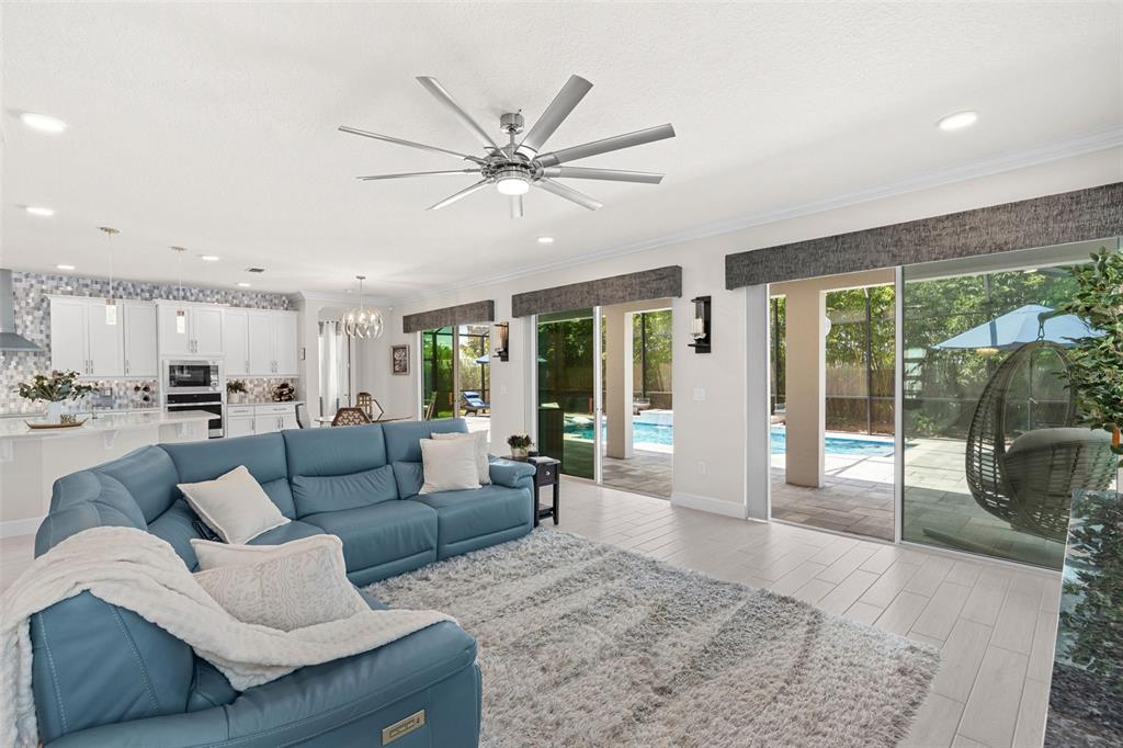 A living room with a blue sectional sofa, shaggy rug, and sliding doors to a pool — 3336 LONE CYPRESS POINT, OVIEDO, FL