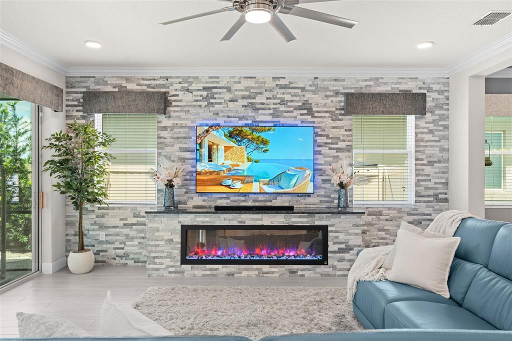 A living room features a stone-tiled accent wall with a built-in fireplace and mounted television — 3336 LONE CYPRESS POINT, OVIEDO, FL