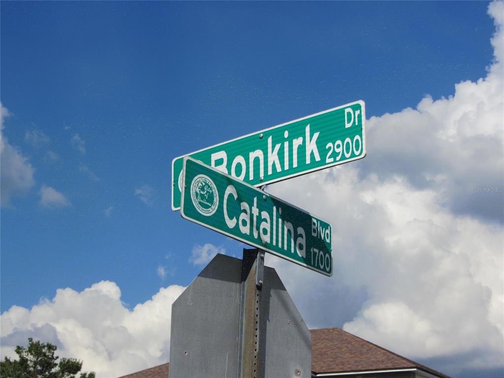 A street sign displays the names Ronkirk Dr and Catalina Blvd against a blue sky — 1684 CATALINA BLVD, DELTONA, FL