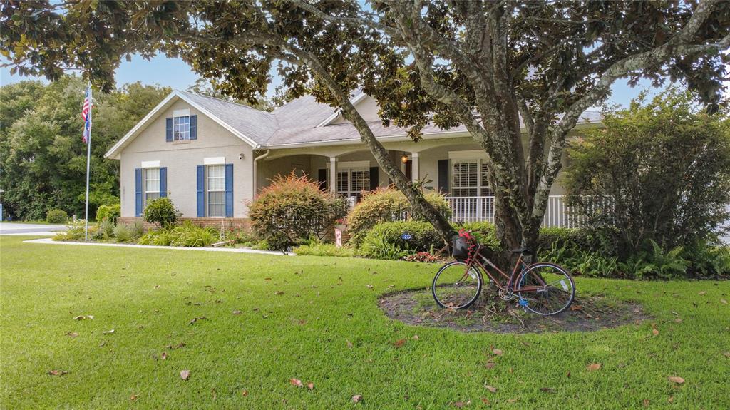 A single-story house with blue shutters and a bicycle parked by a tree in front — 19512 SPRING OAK DRIVE, EUSTIS, FL