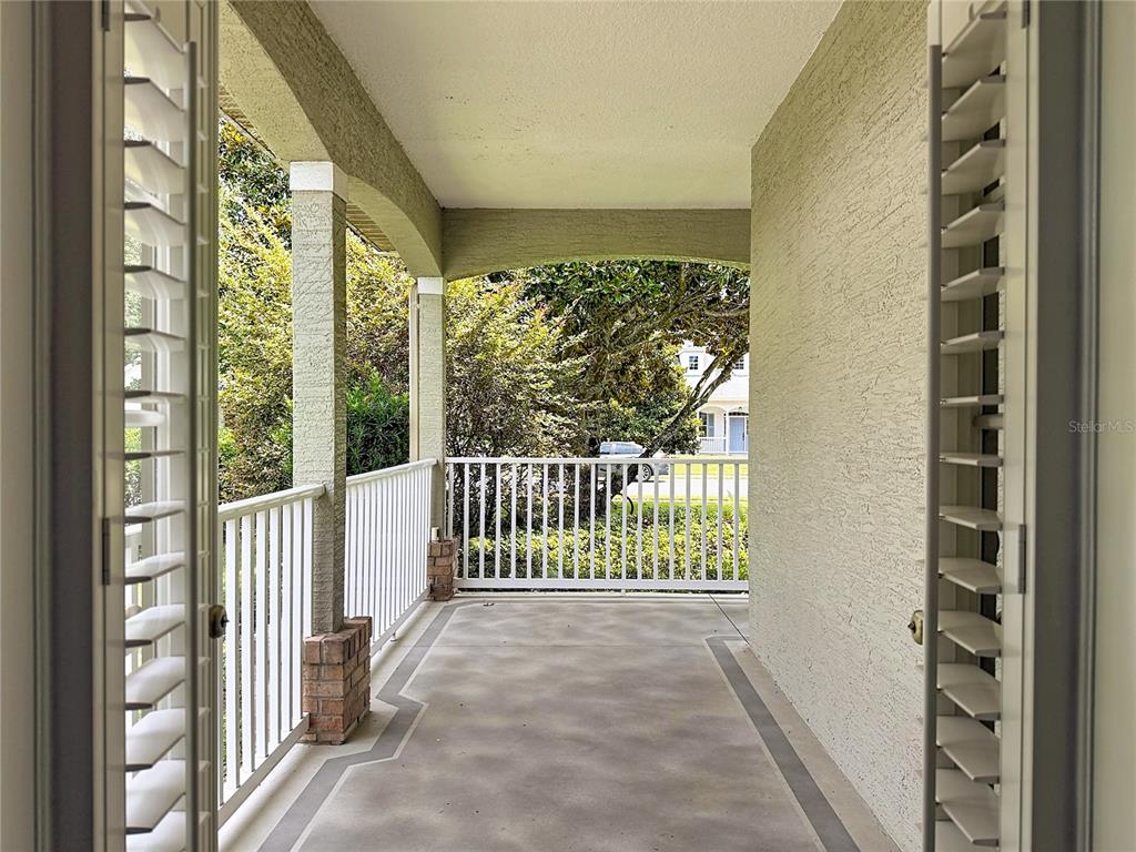 A covered porch features a concrete floor, white railings, and arched architectural details — 19512 SPRING OAK DRIVE, EUSTIS, FL
