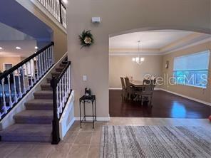 A staircase with a dark wood railing leads to an upper level near a dining room — 17419 BELLA NOVA DRIVE, ORLANDO, FL