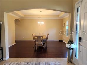 A dining room with dark wood floors, a tray ceiling, and a chandelier — 17419 BELLA NOVA DRIVE, ORLANDO, FL