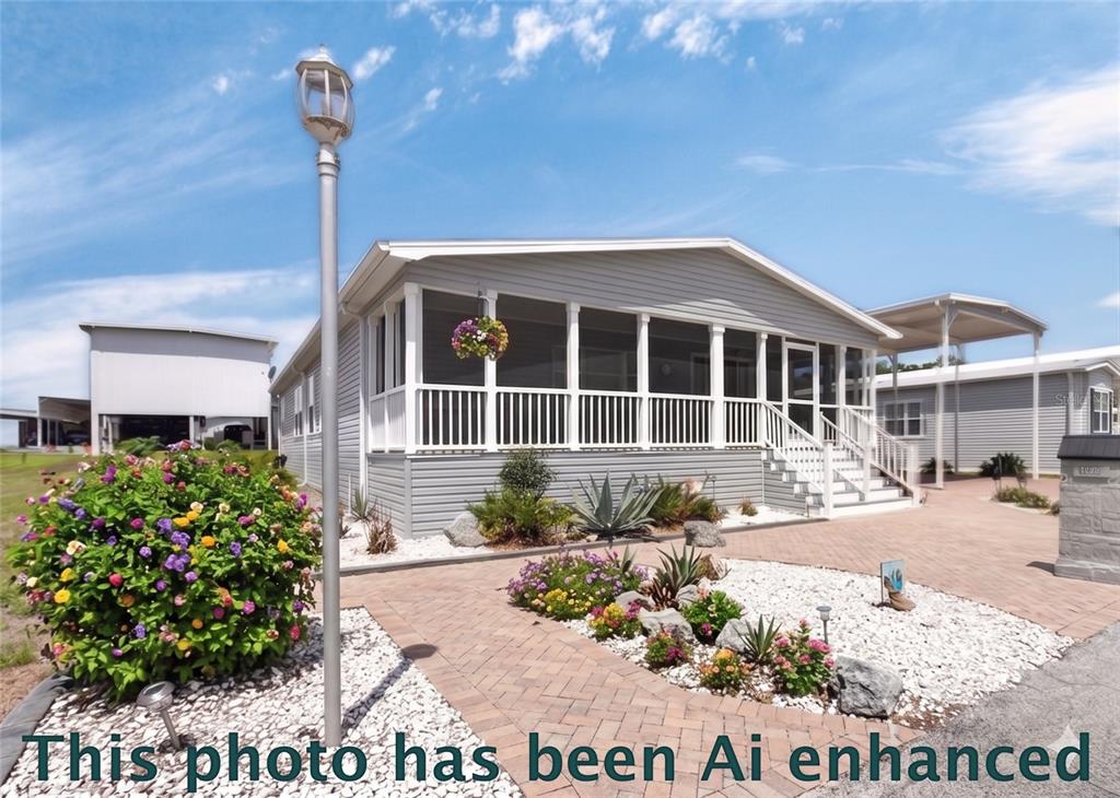 A light gray manufactured home features a screened-in front porch and a brick paver driveway — 10039 STERLING AVENUE, DADE CITY, FL