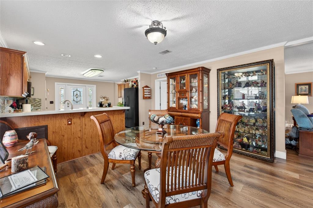 A dining area with a glass table, wooden chairs, and a large display cabinet — 10039 STERLING AVENUE, DADE CITY, FL