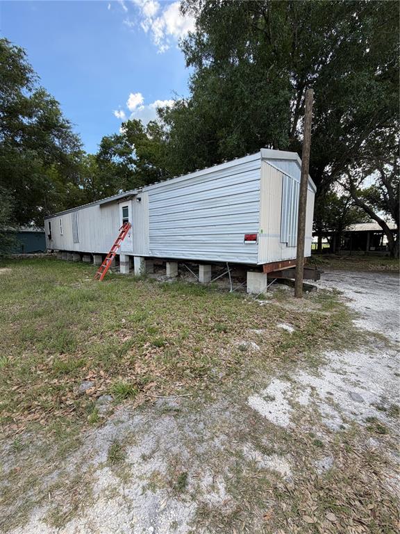 A mobile home sits on concrete block piers in a grassy, partially wooded lot — 1059 NE SUGAR BABE ROAD, ARCADIA, FL