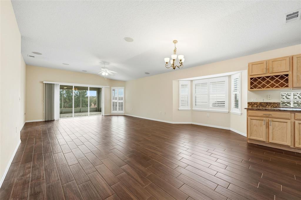 A spacious living room features wood-look tile flooring, a ceiling fan, and a wet bar — 2311 N ANDREA POINT, LECANTO, FL