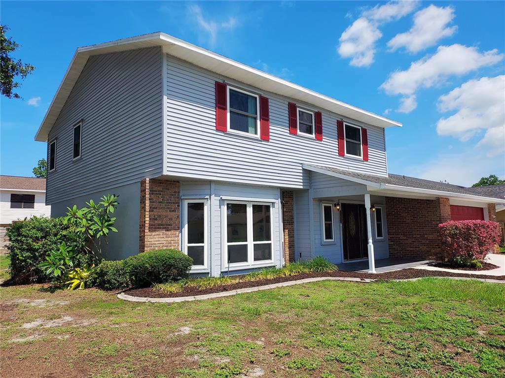 A two-story house with light gray siding, red shutters, and a brick-accented front entryway — 702 HYSSOP PLACE, BRANDON, FL