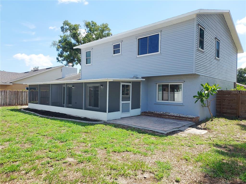 The exterior of a two-story house features light blue siding, a screened-in porch, and a patio — 702 HYSSOP PLACE, BRANDON, FL