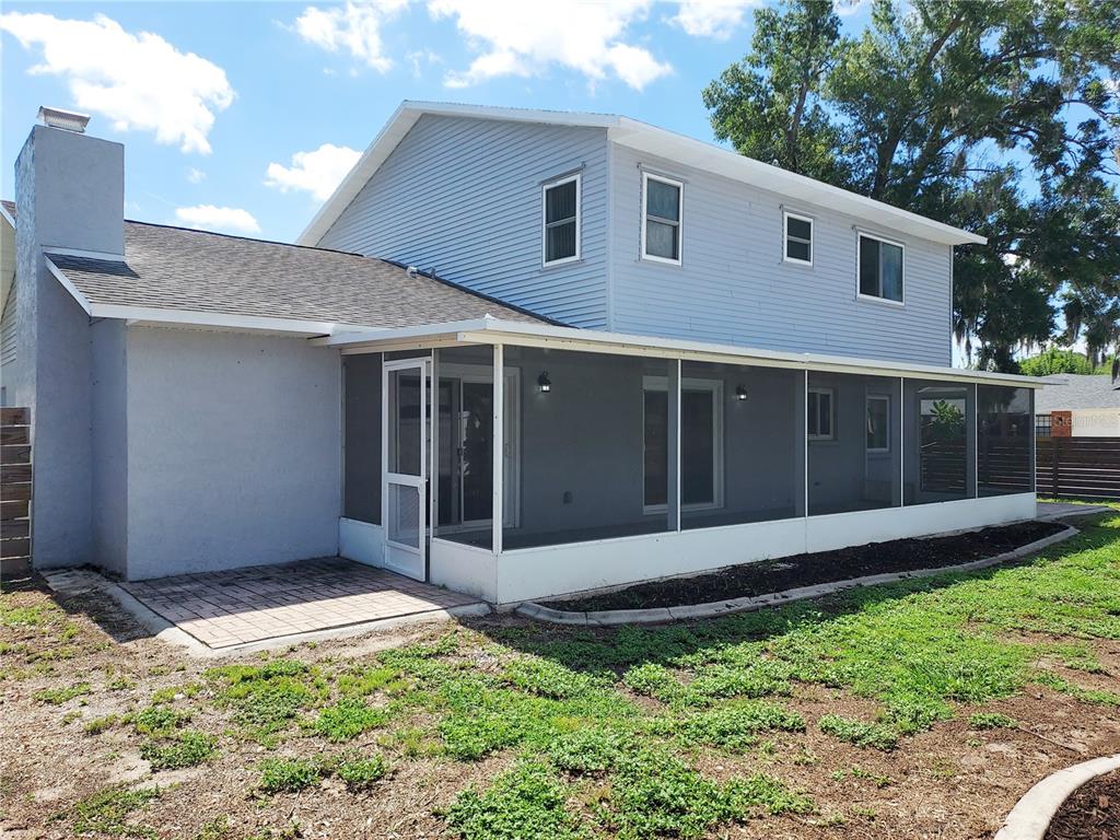 A two-story house with light blue siding, a screened-in porch, and a paved patio area — 702 HYSSOP PLACE, BRANDON, FL