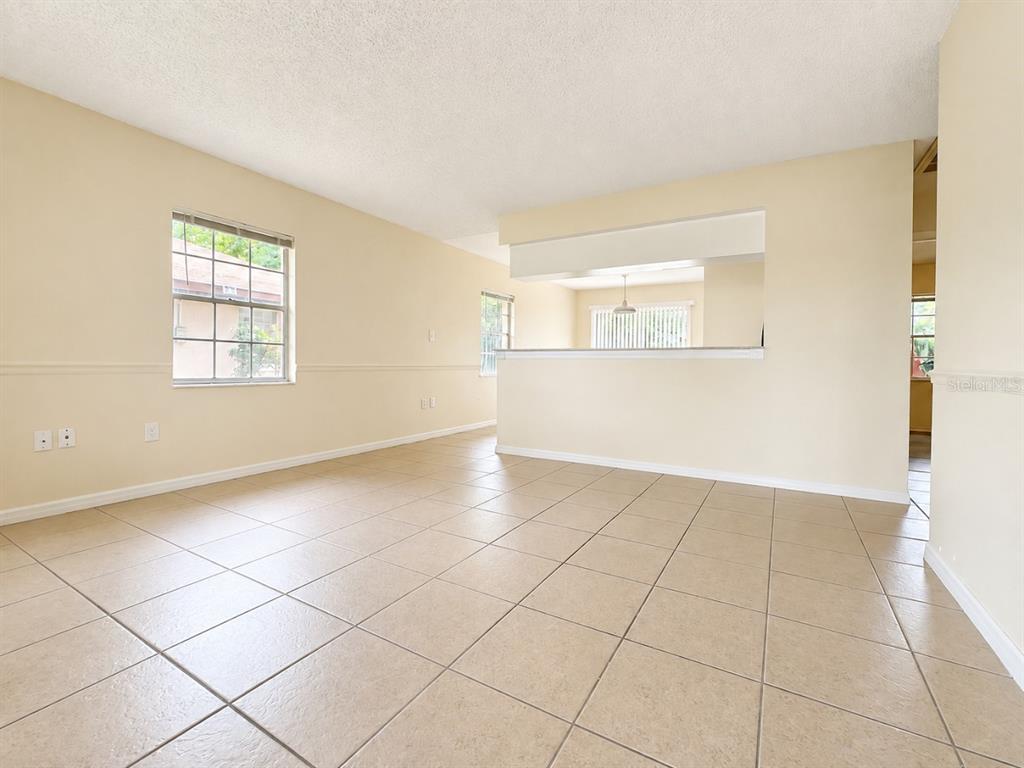 An empty room with beige tile flooring, light-colored walls, and a pass-through window to another area — 3113 WOODHILL ROAD, WINTER HAVEN, FL