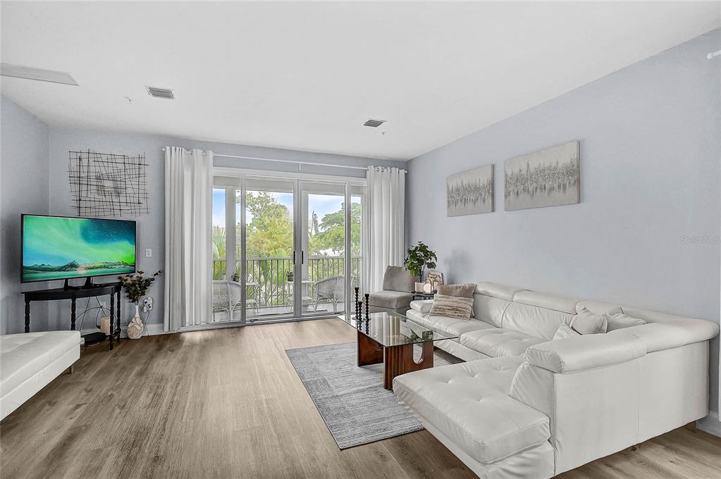 A living room features light wood flooring, a white sectional sofa, and sliding glass balcony doors — 508 FOREST WAY, LONGBOAT KEY, FL
