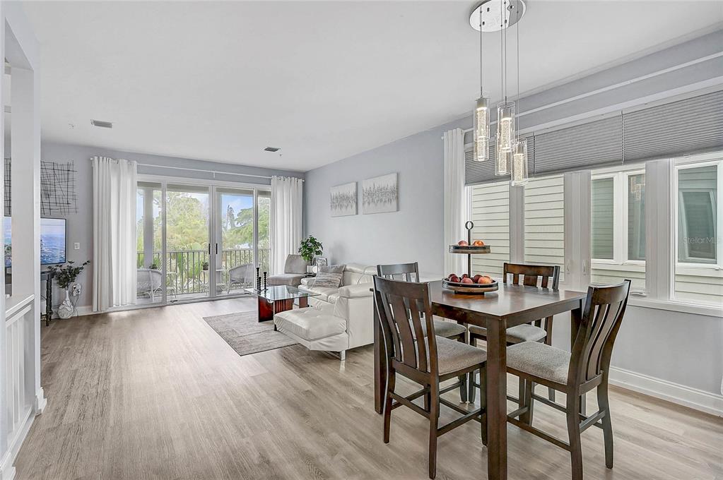 A dining area and living room with light wood floors, white walls, and a balcony view — 508 FOREST WAY, LONGBOAT KEY, FL