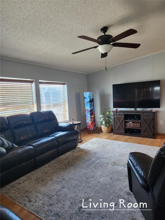 A living room features a dark leather sofa, a television on a stand, and ceiling fan — 1001 STARKEY ROAD UNIT 758, LARGO, FL