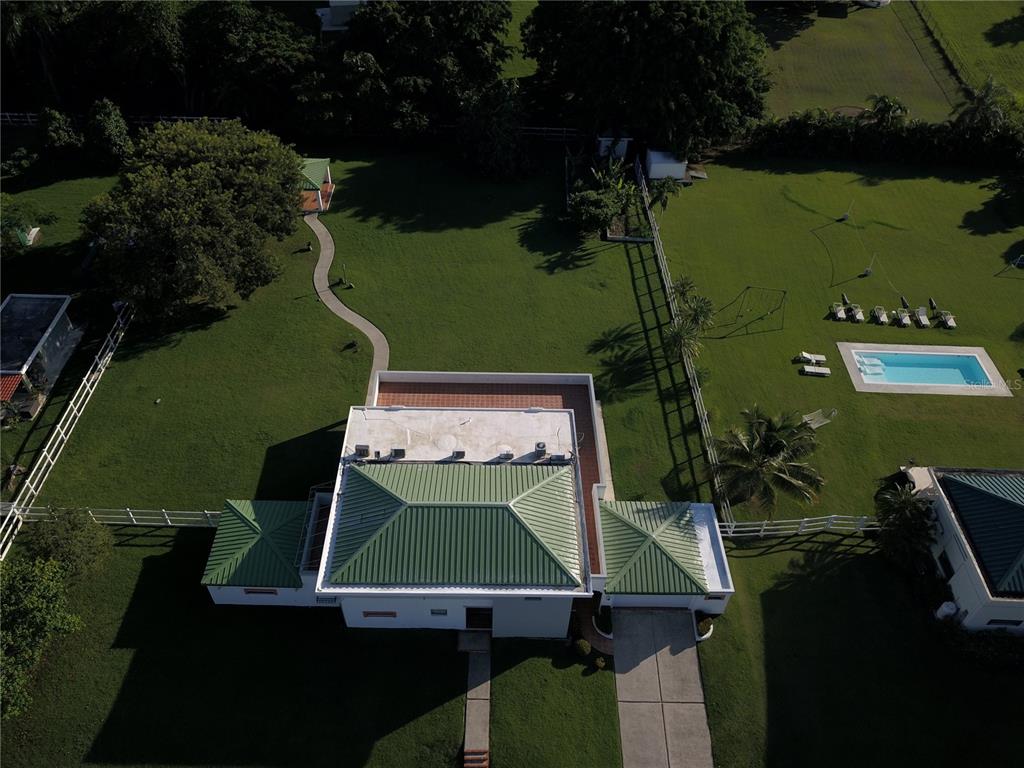 An aerial view shows a house with a green metal roof, pool, and large yard — Ave. Hacienda Margarita URB. HACIENDA MARGARITA UNIT 8, LUQUILLO, PR