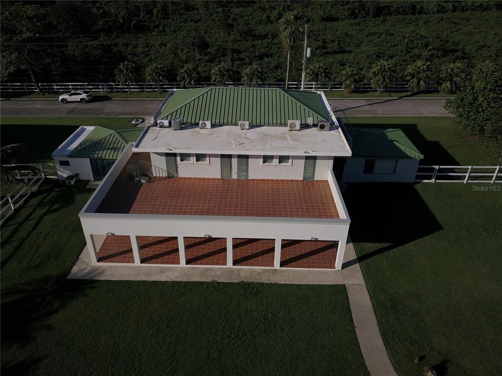 An aerial view shows a white building with a green metal roof and a terrace — Ave. Hacienda Margarita URB. HACIENDA MARGARITA UNIT 8, LUQUILLO, PR