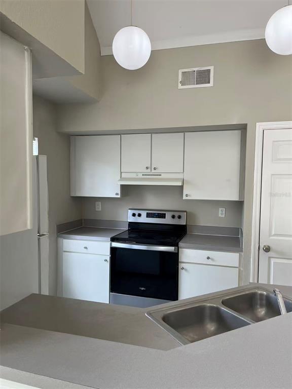 A kitchen features white cabinets, stainless steel appliances, and a double-basin sink on the counter — 10452 WHITE LAKE COURT UNIT 10452, TAMPA, FL