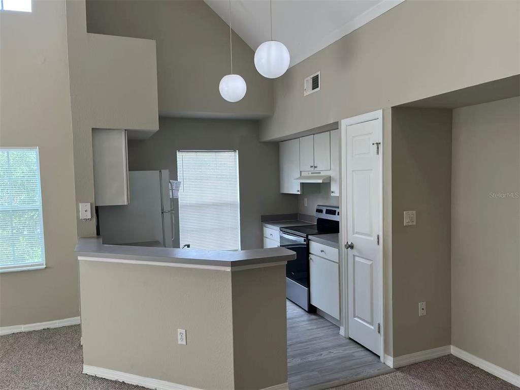 A kitchen with white cabinets, stainless steel appliances, and a breakfast bar overlooks a room — 10452 WHITE LAKE COURT UNIT 10452, TAMPA, FL