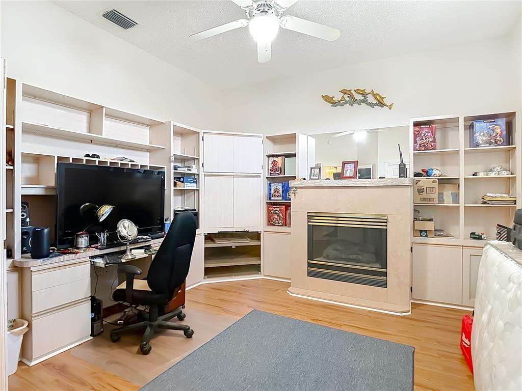 A room with wood flooring, a fireplace, built-in shelving, and a desk with a computer — 8410 MAYBELLE DRIVE, WEEKI WACHEE, FL
