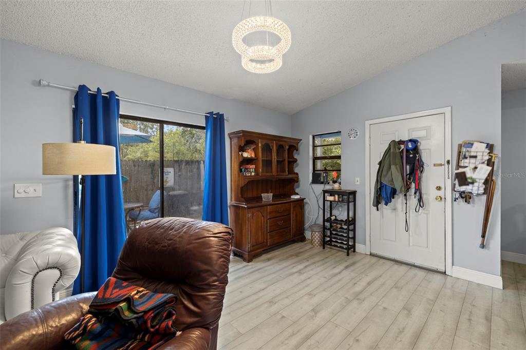 A living room features light gray walls, wood-look flooring, a hutch, and a sliding glass door — 1335 15TH STREET, PALM HARBOR, FL