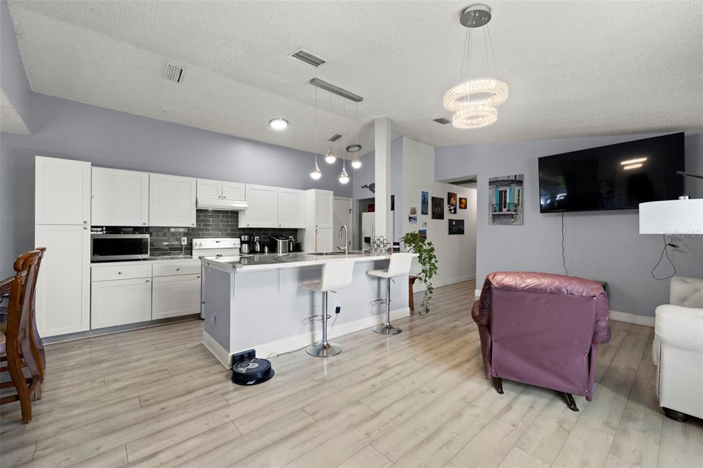 An open-concept kitchen and living area features white cabinetry, a breakfast bar, and light flooring — 1335 15TH STREET, PALM HARBOR, FL