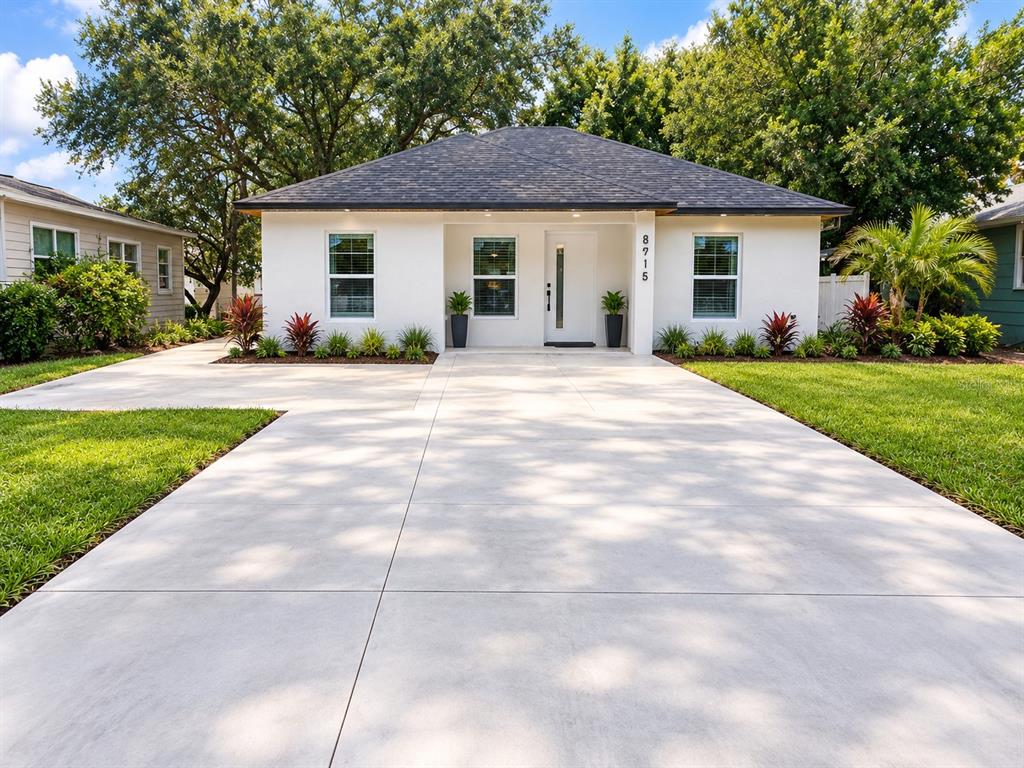 A white, single-story house with a dark roof and a large concrete driveway — 8915 N WILLOW AVENUE, TAMPA, FL