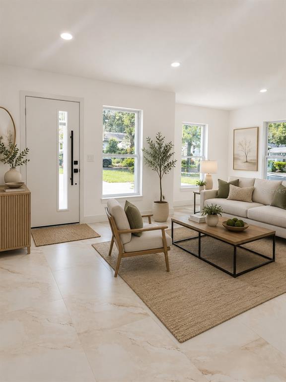 A bright living room features light tile floors, a modern front door, and neutral furniture — 8915 N WILLOW AVENUE, TAMPA, FL