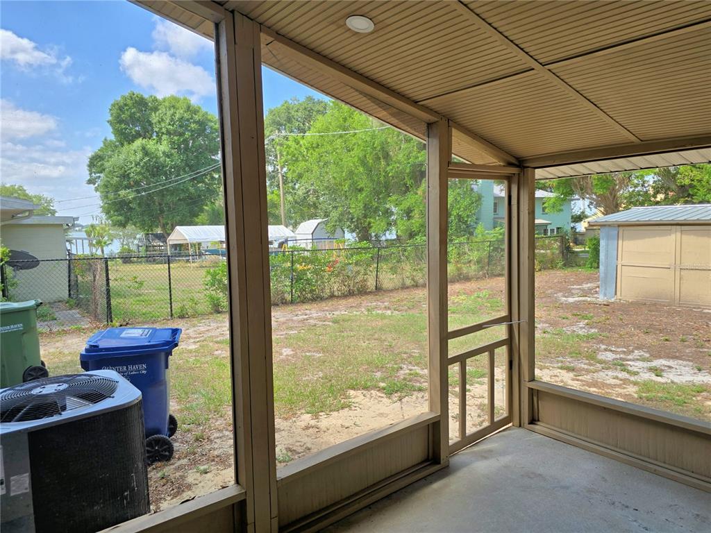 A screened-in porch overlooks a fenced backyard with a shed and a blue trash bin — 1919 19TH STREET NW, WINTER HAVEN, FL