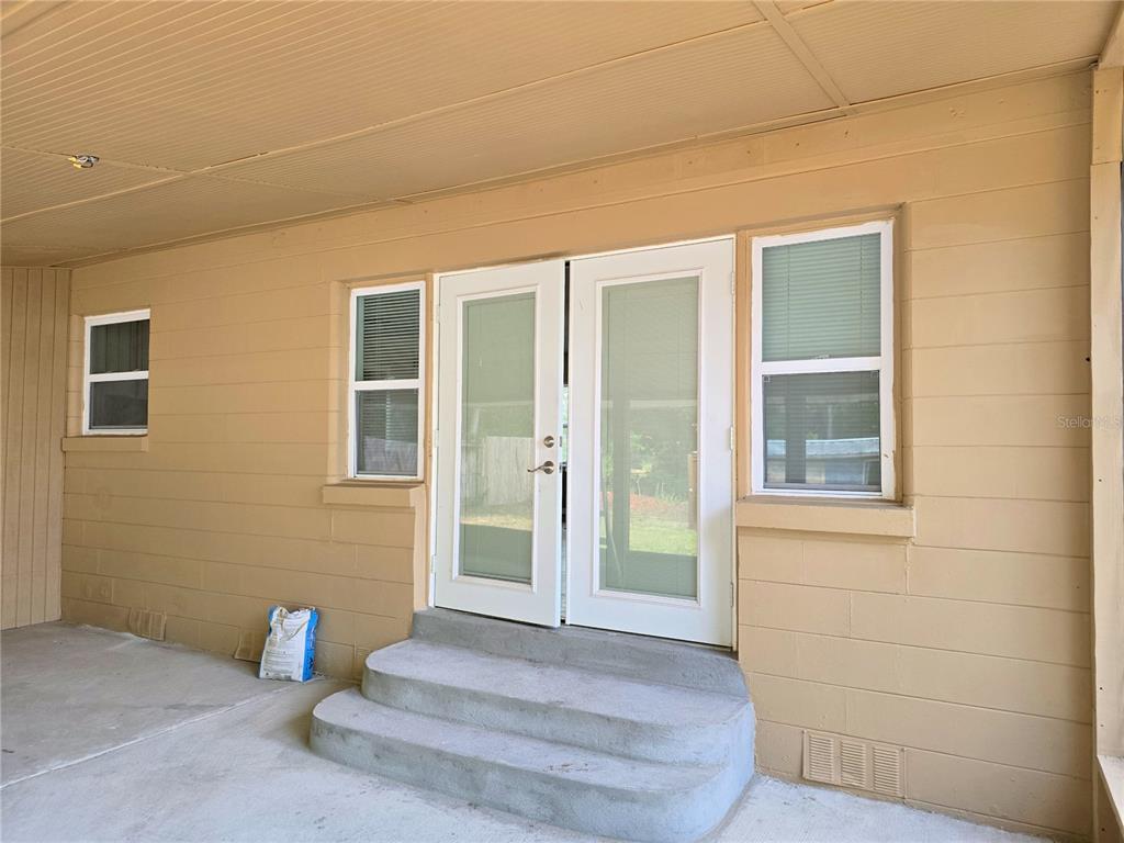 A tan exterior wall features a set of double glass doors and two windows — 1919 19TH STREET NW, WINTER HAVEN, FL