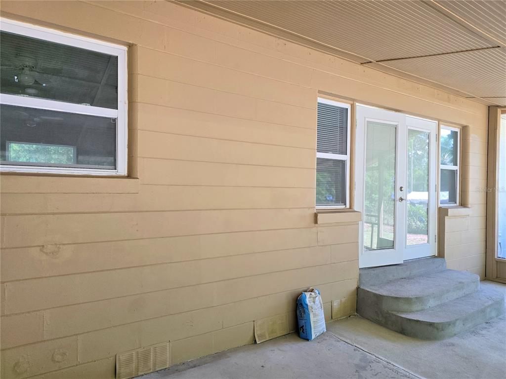 A tan exterior wall features a window, double glass doors, and concrete steps — 1919 19TH STREET NW, WINTER HAVEN, FL