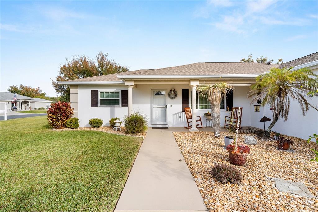 A single-story house with a white exterior, a covered entryway, and a gravel front yard — 8516 SE 137TH LOOP, SUMMERFIELD, FL