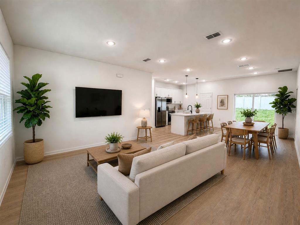 An open-concept living room and kitchen featuring light wood flooring and neutral furniture — 10032 N DELTONA BOULEVARD, DUNNELLON, FL